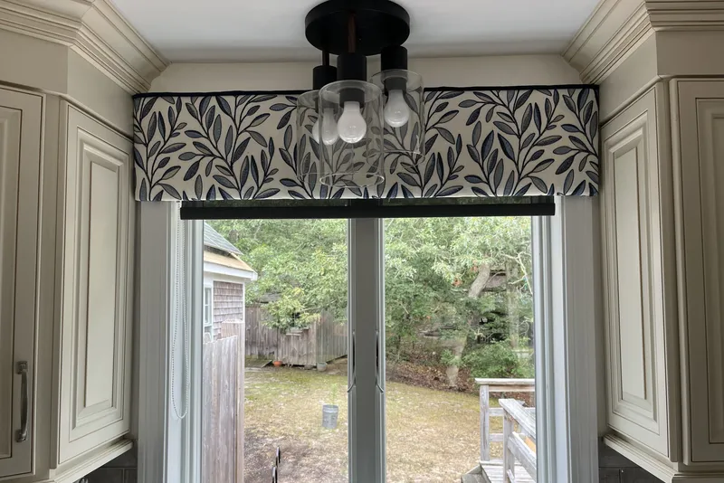 Bright white kitchen displaying custom-installed patterned fabric cornice.