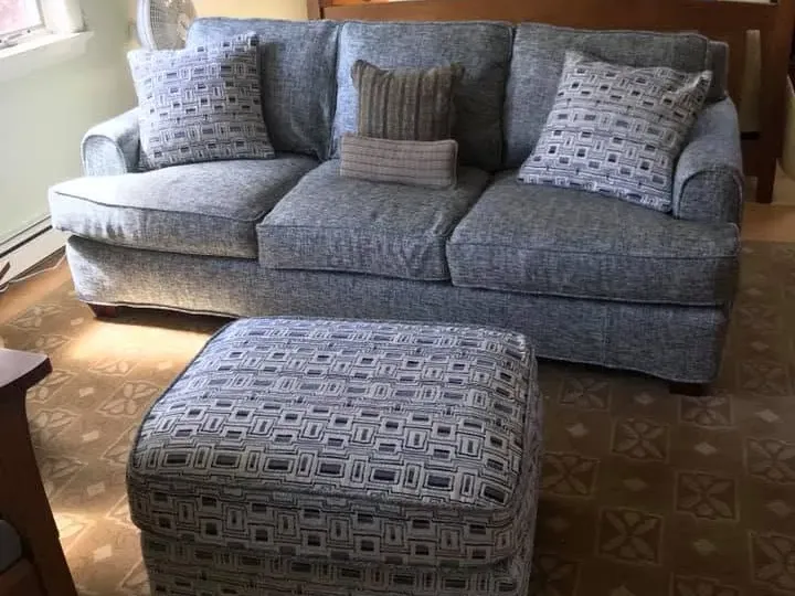 Beautifully fitted custom fabric slipcovers on a living room sofa and matching ottoman in Truro, Cape Cod.