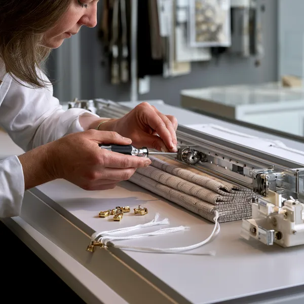 A close-up view of specialized window shade repair work being performed on a premium woven window shade mechanism.
